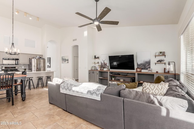 living room featuring high vaulted ceiling and ceiling fan with notable chandelier