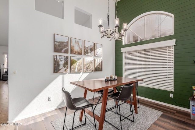 dining space with a high ceiling, an inviting chandelier, and hardwood / wood-style floors