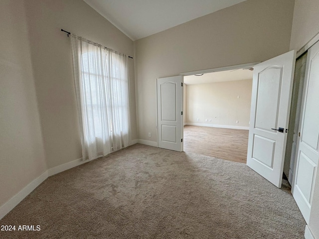 unfurnished room featuring light colored carpet and vaulted ceiling