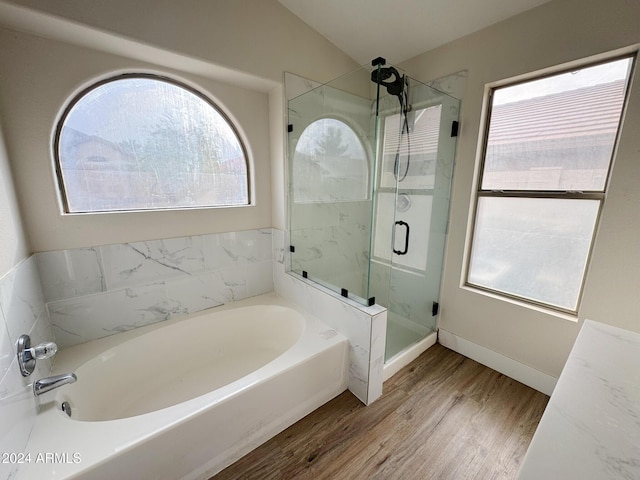 bathroom featuring shower with separate bathtub, hardwood / wood-style flooring, and lofted ceiling