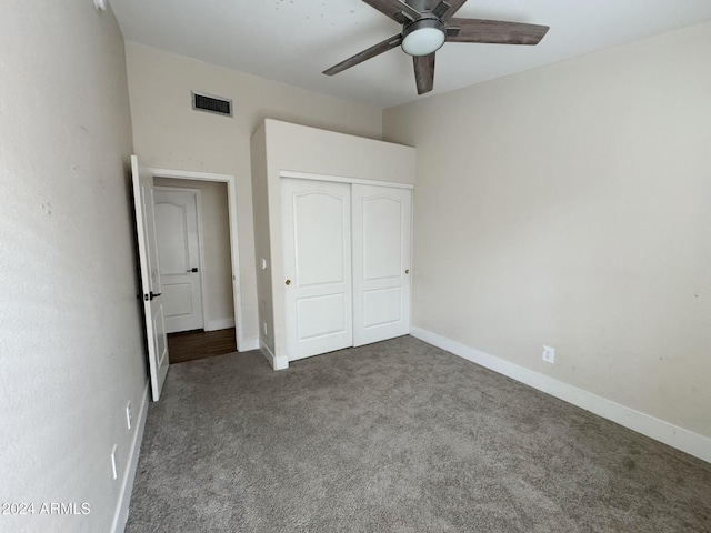 unfurnished bedroom with dark colored carpet, ceiling fan, and a closet