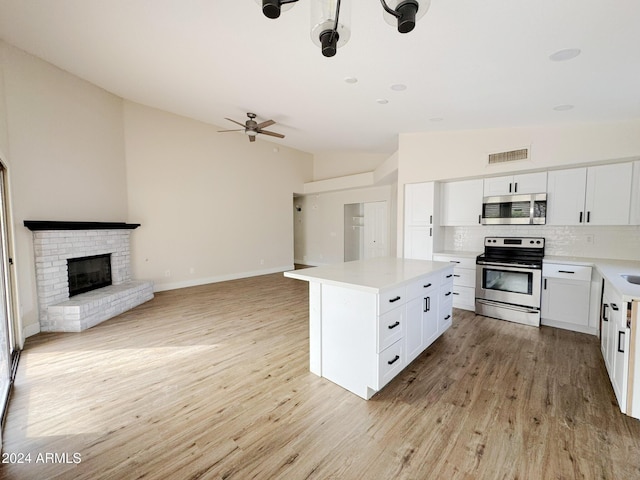 kitchen featuring a center island, light wood-type flooring, tasteful backsplash, white cabinetry, and stainless steel appliances