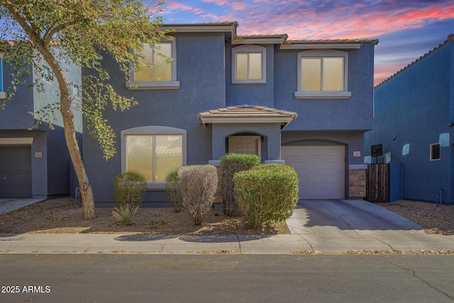 view of front of home with an attached garage, a tiled roof, concrete driveway, and stucco siding