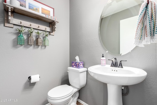 half bath featuring toilet, baseboards, and a textured wall