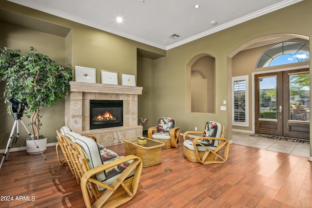 living room with a tiled fireplace, hardwood / wood-style flooring, and crown molding