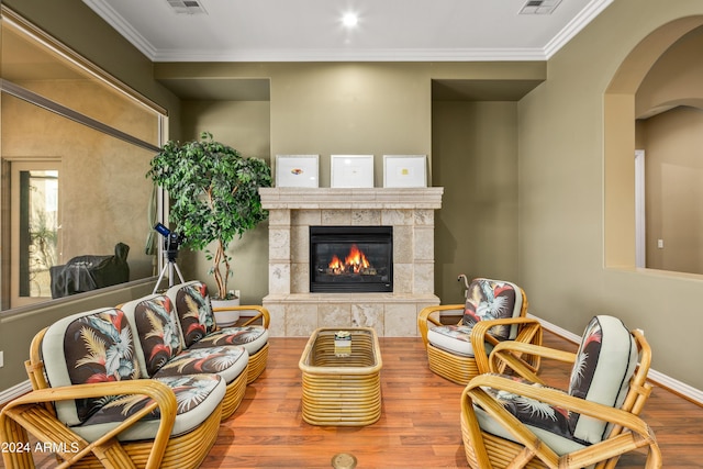 living room with ornamental molding, a tiled fireplace, and hardwood / wood-style floors