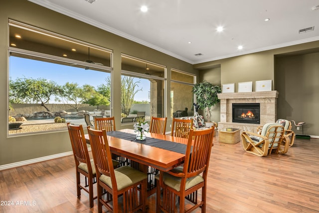 dining space featuring crown molding, a fireplace, and light hardwood / wood-style flooring