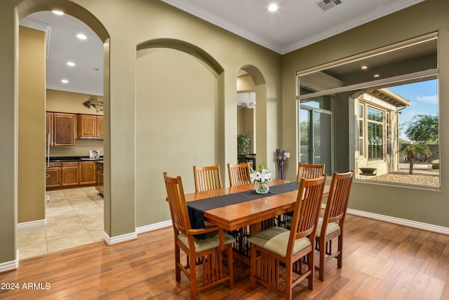 dining space with crown molding and light hardwood / wood-style flooring