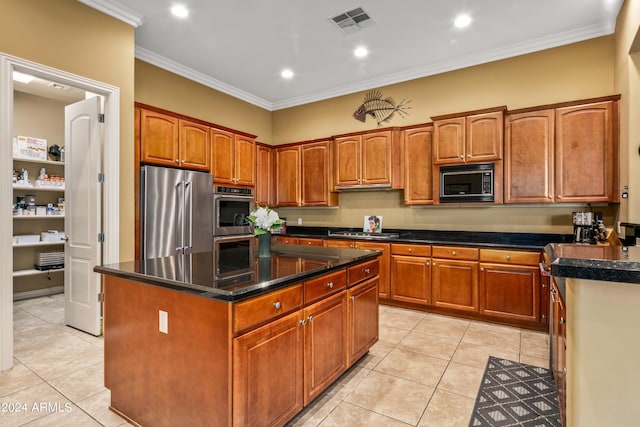 kitchen with light tile patterned floors, appliances with stainless steel finishes, a kitchen island, and crown molding