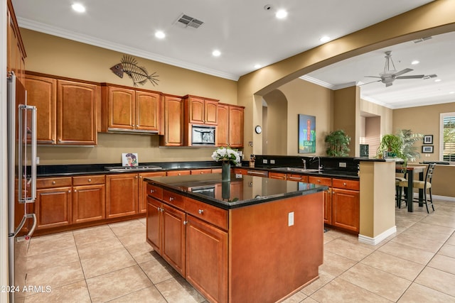 kitchen with ceiling fan, stainless steel appliances, kitchen peninsula, and a kitchen island