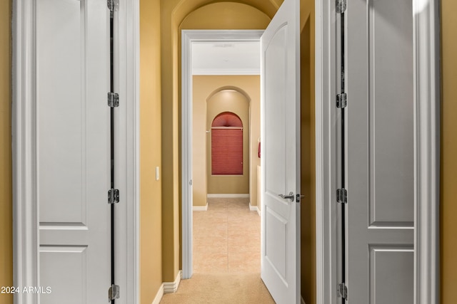 hallway featuring ornamental molding and light tile patterned floors