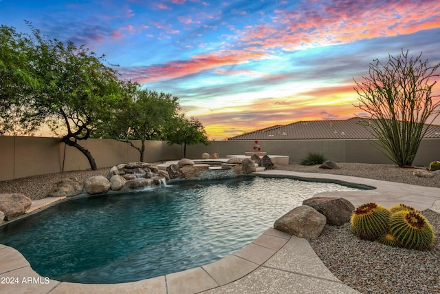 pool at dusk with an in ground hot tub and pool water feature