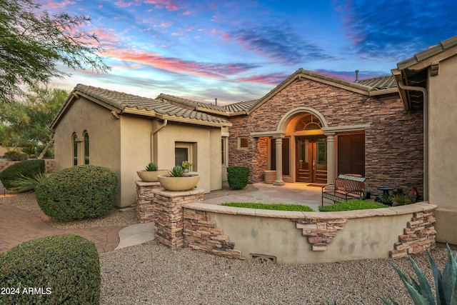 back house at dusk featuring a patio