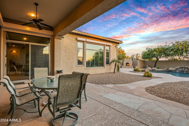 patio terrace at dusk featuring a fenced in pool and ceiling fan