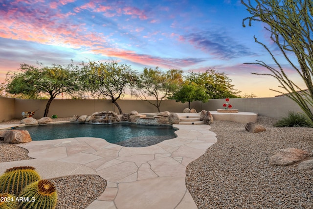 pool at dusk with a patio area