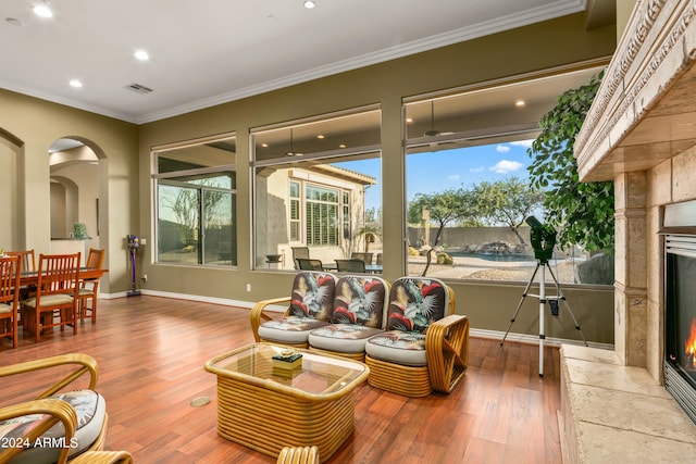 living room with wood-type flooring, ornamental molding, and a premium fireplace