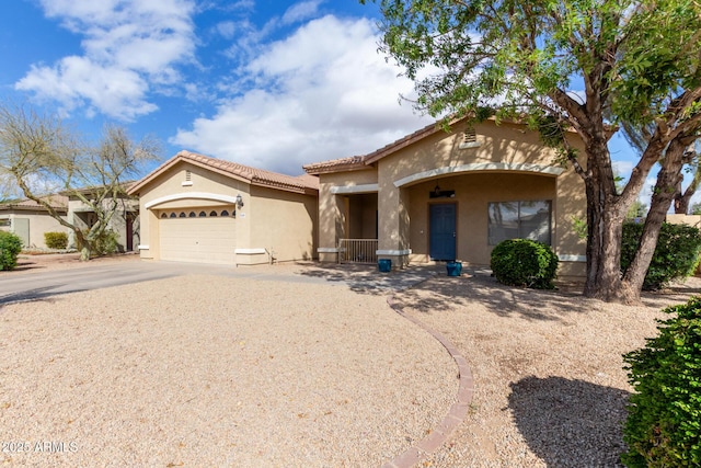 mediterranean / spanish home featuring a garage, driveway, a tiled roof, and stucco siding