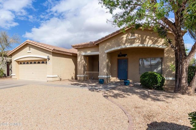 view of front of house with an attached garage, covered porch, a tile roof, concrete driveway, and stucco siding