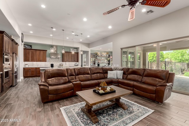 living room featuring a ceiling fan, visible vents, recessed lighting, and light wood-style flooring
