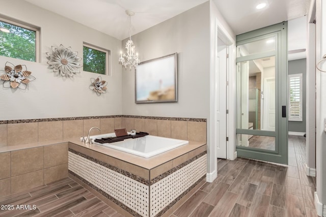 full bathroom with recessed lighting, a garden tub, wood finish floors, and a chandelier