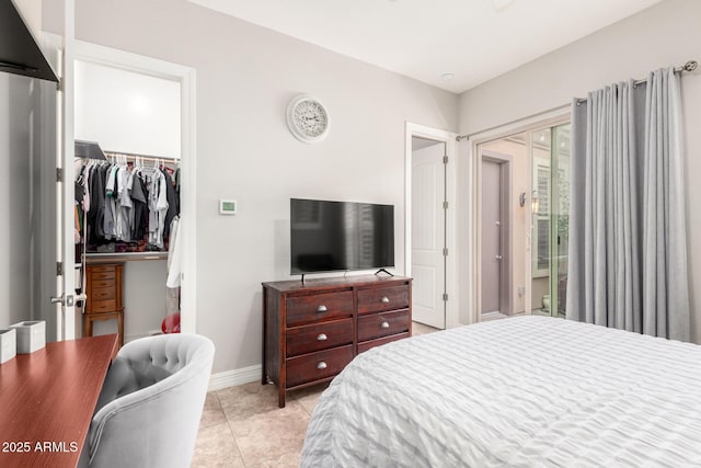 bedroom featuring a walk in closet, baseboards, light tile patterned flooring, and a closet