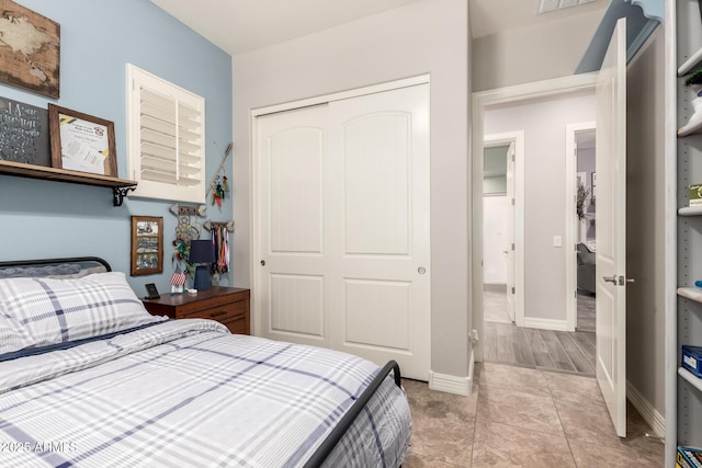 bedroom featuring light tile patterned floors, baseboards, visible vents, and a closet