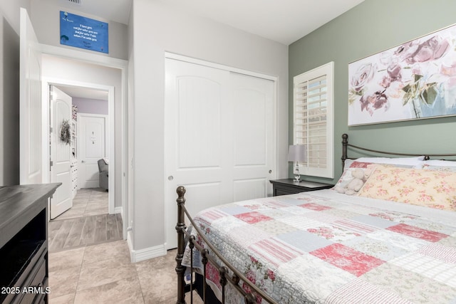 bedroom with baseboards, a closet, and light tile patterned floors