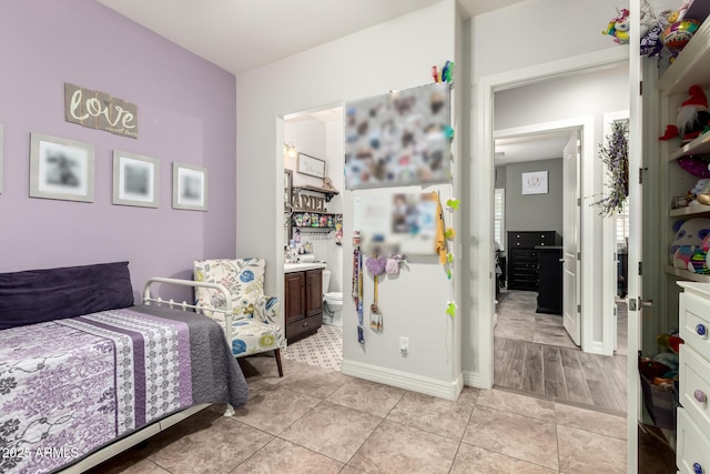bedroom with connected bathroom, baseboards, and light tile patterned floors