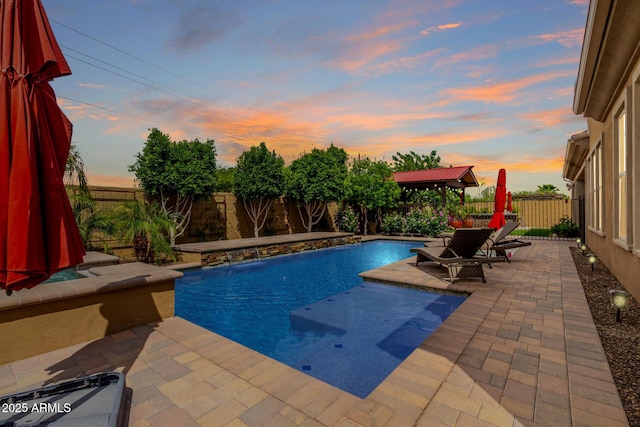 pool at dusk with a fenced backyard, a gazebo, a patio, and a fenced in pool