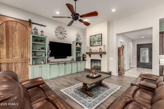 living area featuring light wood-style flooring, baseboards, recessed lighting, a ceiling fan, and a fireplace