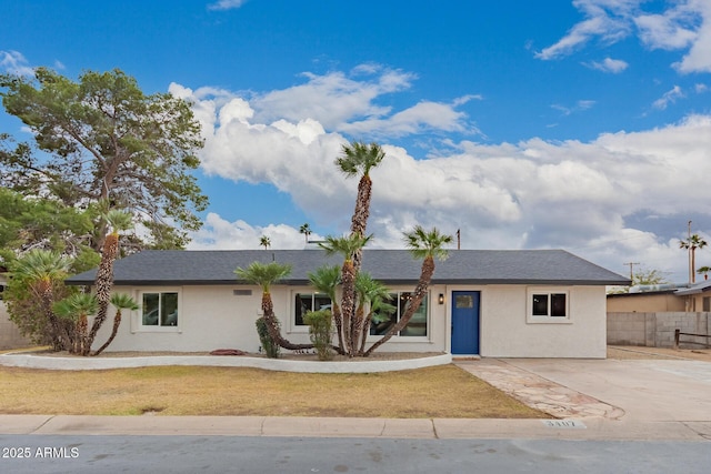 ranch-style house with stucco siding, roof with shingles, and fence