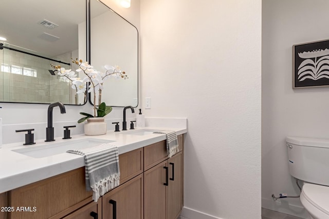 bathroom featuring a sink, visible vents, toilet, and double vanity