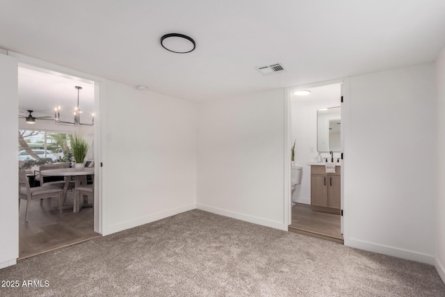 spare room featuring baseboards, visible vents, carpet floors, and an inviting chandelier