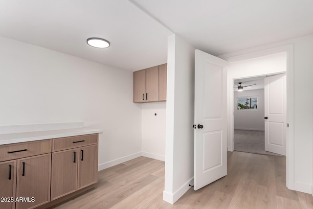 clothes washing area featuring light wood-style flooring, cabinet space, baseboards, and hookup for an electric dryer