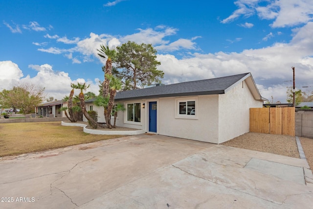 ranch-style home featuring a gate, stucco siding, a front yard, and fence