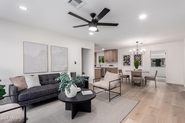 living room with visible vents, baseboards, recessed lighting, ceiling fan with notable chandelier, and light wood-style floors