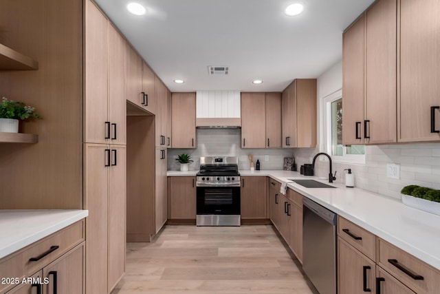 kitchen featuring visible vents, a sink, tasteful backsplash, appliances with stainless steel finishes, and light wood finished floors