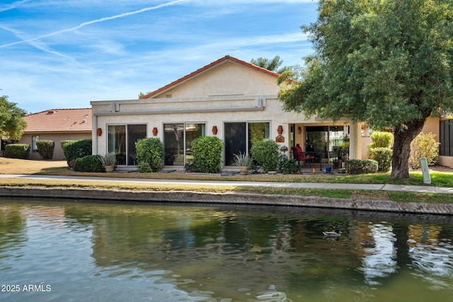 back of house featuring a water view and stucco siding