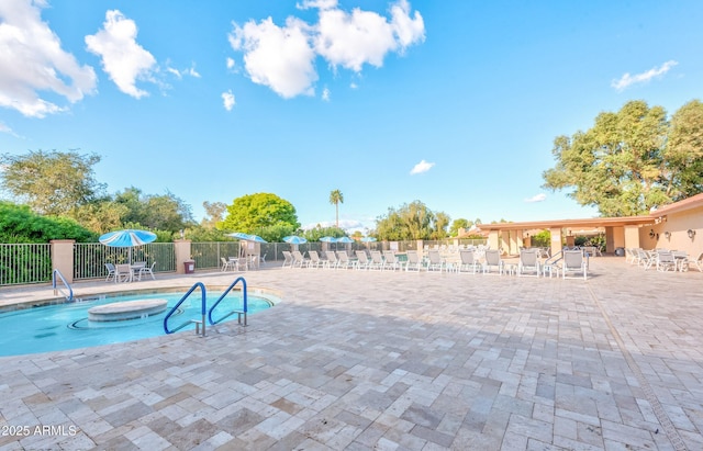community pool with fence, a hot tub, and a patio