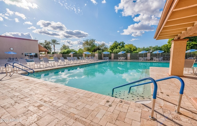 community pool with a patio area and fence