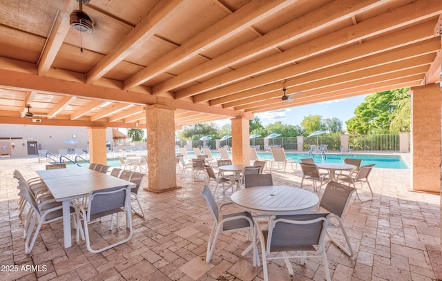 view of patio with a ceiling fan, outdoor dining area, fence, and a community pool