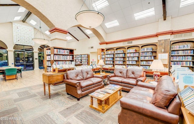 living room with arched walkways, high vaulted ceiling, wall of books, beam ceiling, and ornate columns