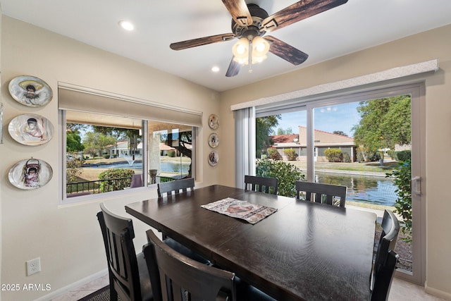 dining room with a water view, baseboards, light colored carpet, and recessed lighting