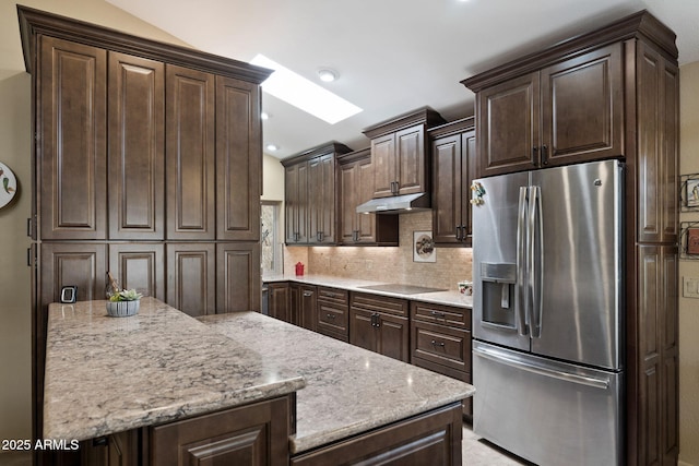 kitchen featuring dark brown cabinetry, under cabinet range hood, a skylight, and stainless steel fridge with ice dispenser