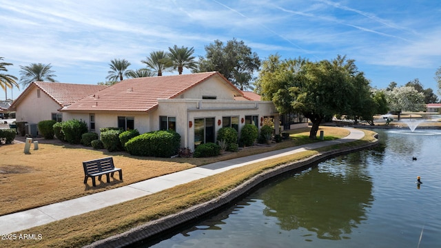 exterior space featuring a tiled roof, a water view, and stucco siding