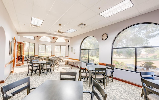 dining area with arched walkways, visible vents, ceiling fan, a drop ceiling, and baseboards
