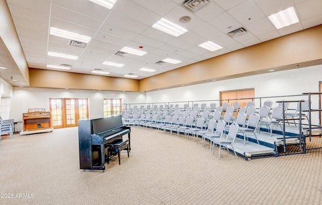 exercise room featuring a high ceiling, a drop ceiling, carpet flooring, and visible vents