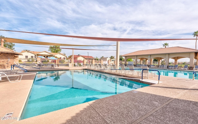 community pool featuring a patio, fence, and a residential view