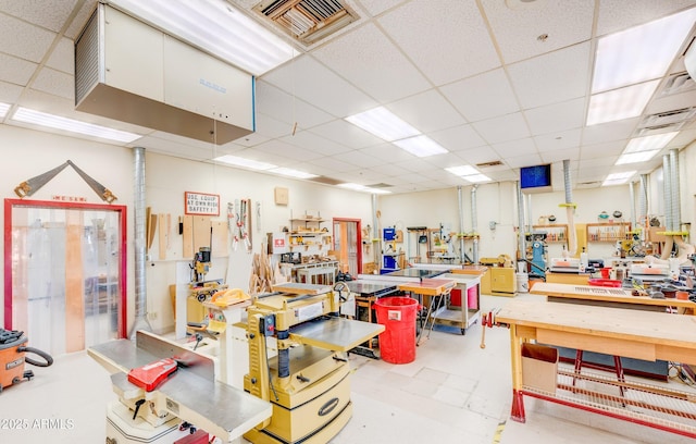 miscellaneous room featuring a workshop area, a drop ceiling, and visible vents