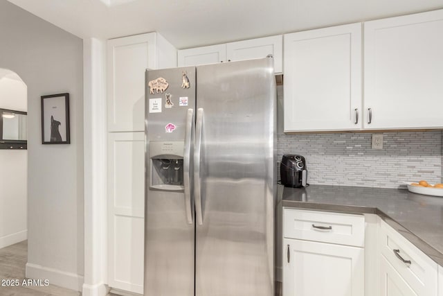 kitchen with tasteful backsplash, baseboards, white cabinetry, and stainless steel fridge with ice dispenser